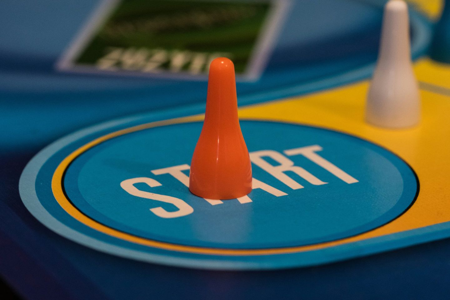 An orange game piece standing on the START circle of a board game